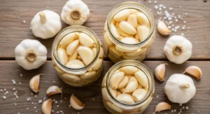Close-up of a glass jar filled with yellow-gold lacto-fermented garlic recipe cloves submerged in brine.