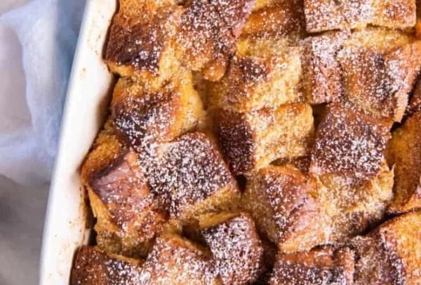 Brioche French toast casserole topped with syrup and berries in a baking dish