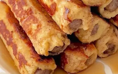 Plate of French Toast Roll-Ups drizzled with syrup and sprinkled with powdered sugar.