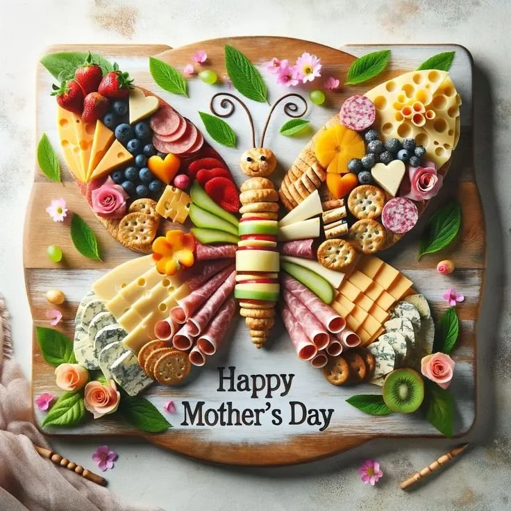Colorful Mother's Day charcuterie board with cheeses, fruits, and flowers.