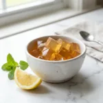 Finished jello recipe for weight loss cubes in white ceramic bowl with lemon on marble